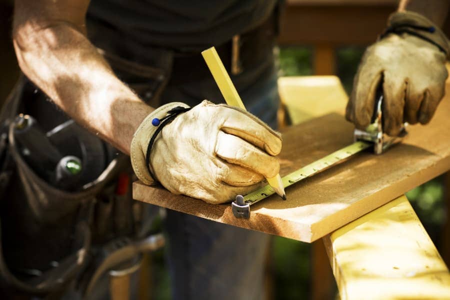 A carpenter measures a plank before cutting
