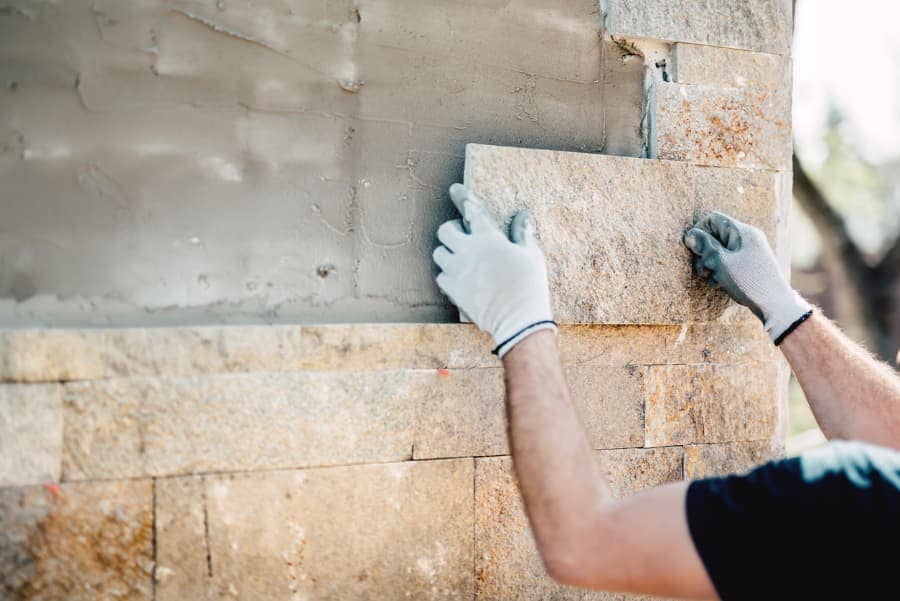 Worker installing stone veneer to building’s foundation