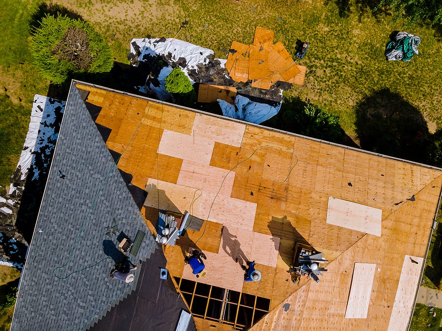 Aerial view of roof construction on a residential home. New roof shingles being installed.