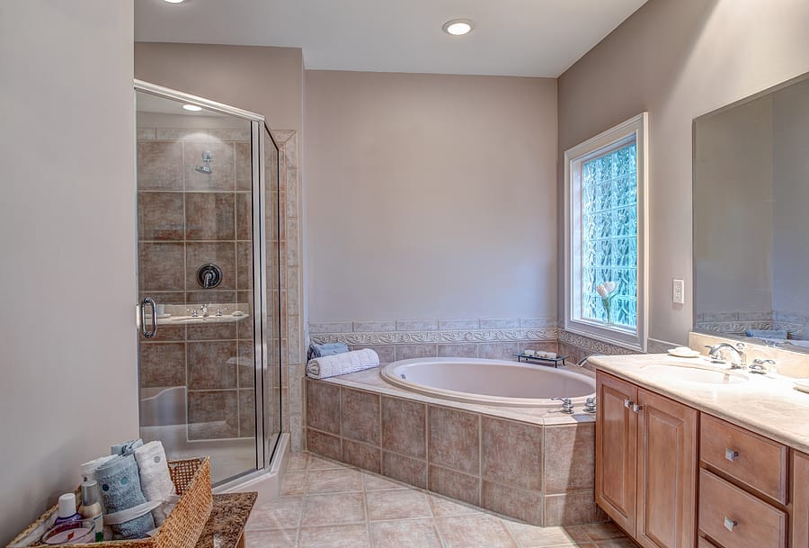 Beautiful bathroom with whirlpool bathtub and separate shower and a large glass block window.