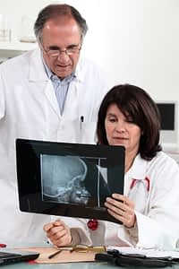 A doctor looking at a brain tumor with his assistant.