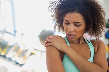 Woman at gym experiencing shoulder pain