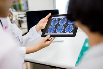 Doctor and patient looking at brain scans on tablet